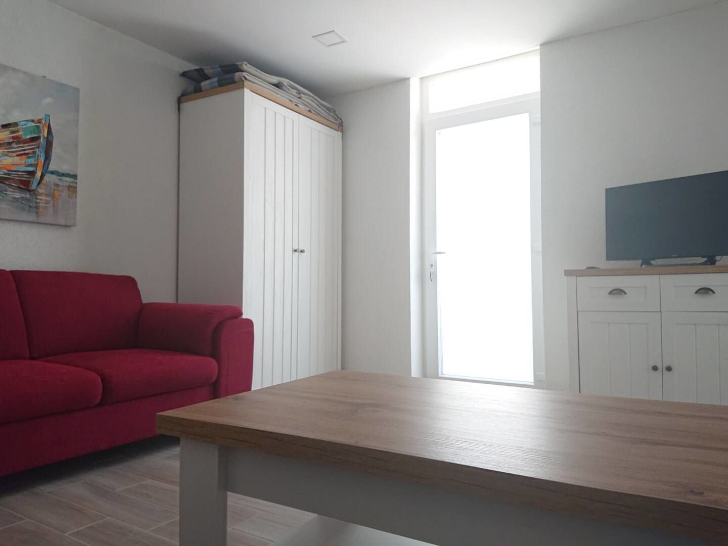Living room with a red sofa, television cabinet and wardrobe