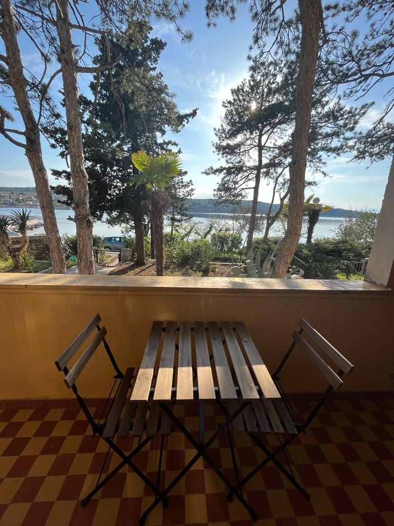 Balcony table and chairs with the sea between the trees