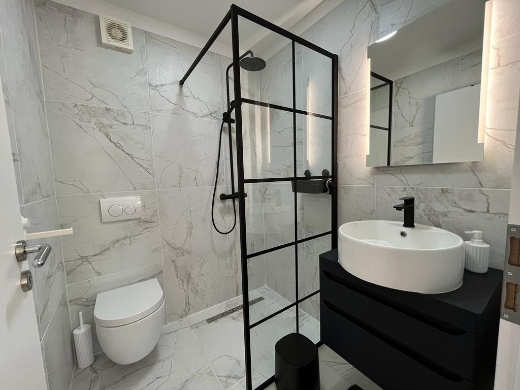 Bathroom in white marble-effect tiles with a black-framed walk-in shower