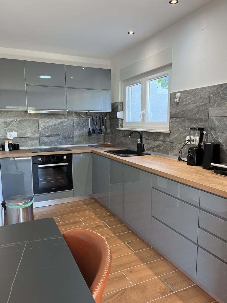 Grey fitted kitchen with an oven, hob and wooden worktop