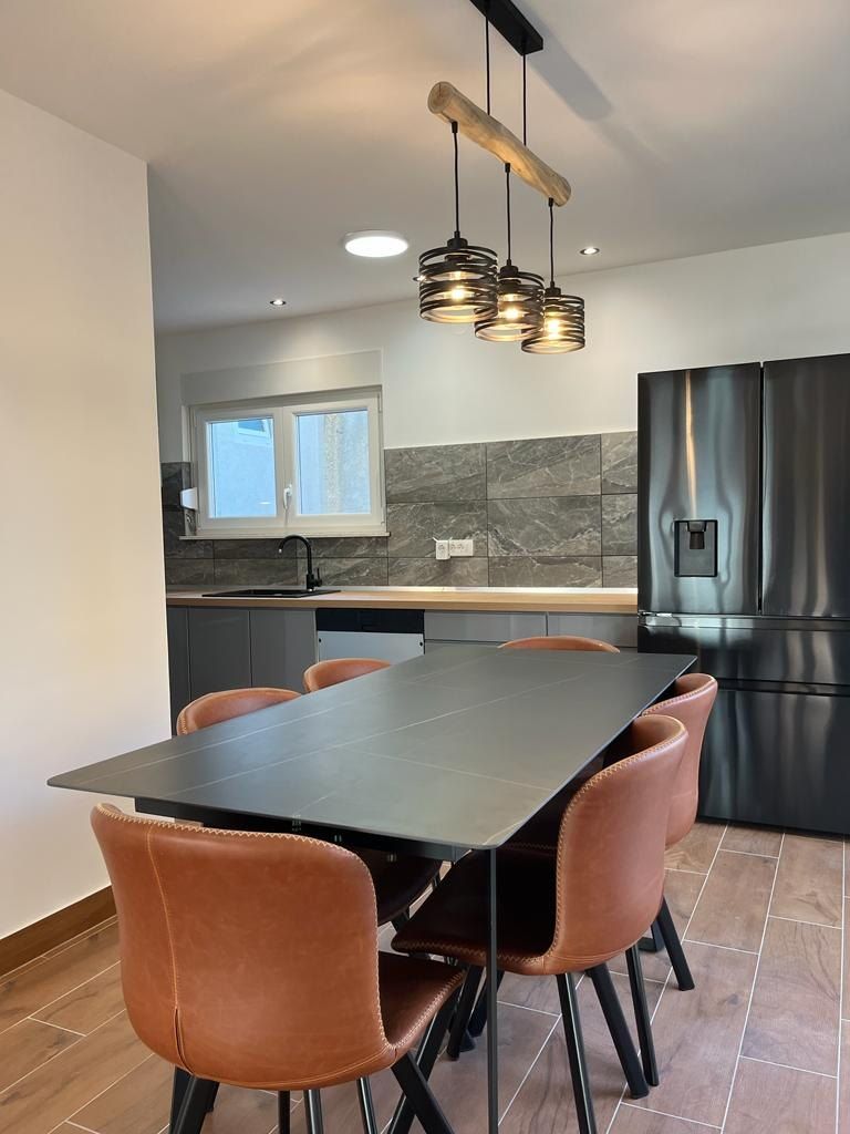 Kitchen with a large black fridge and a dining table with leather chairs